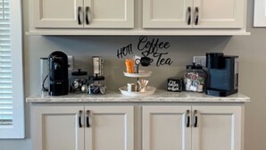 Una cocina con armarios blancos, un espacio para café y un cartel que dice 'Café y Té'.