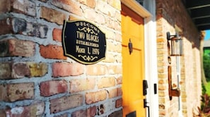 A brick wall with a sign that reads "WELCOME TWO BLOCKS ESTABLISHED MARCH 1, 1976".