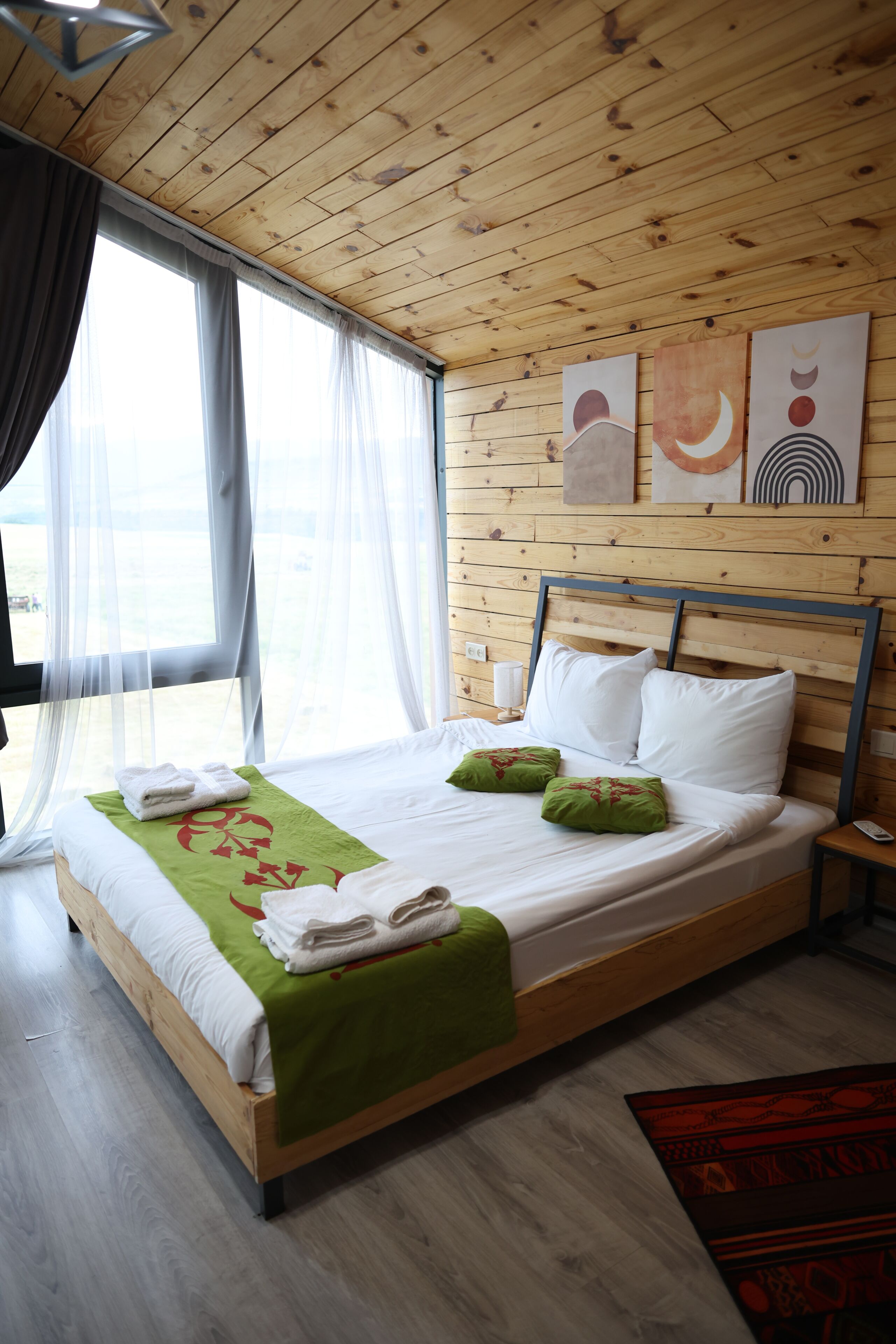 A wooden-paneled bedroom with a bed, white bedding, and artwork on the wall.