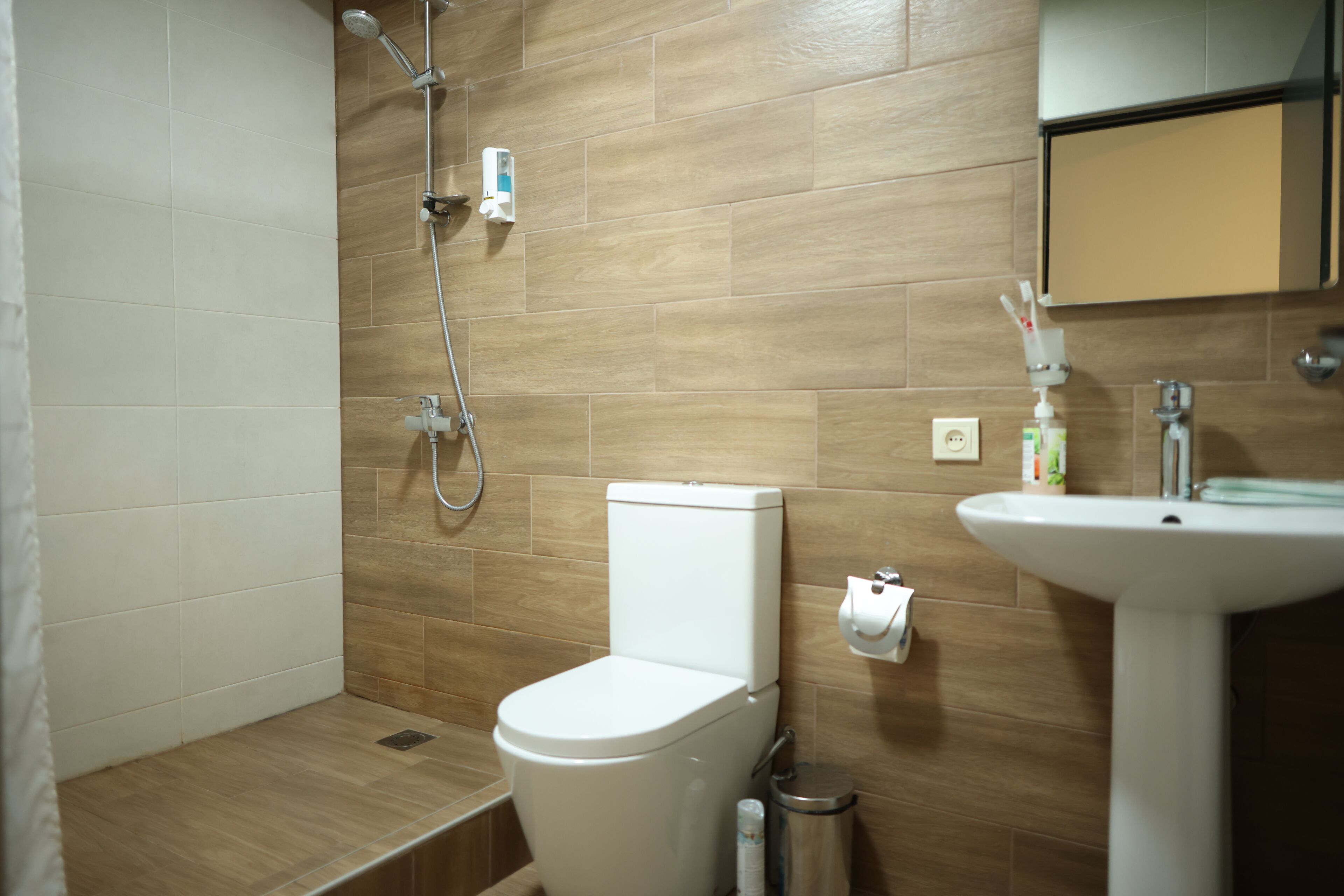 Un baño con ducha, inodoro, lavabo y un espejo sobre el lavabo.