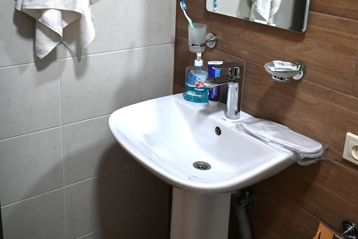 Un baño con un lavamanos blanco, un espejo y una toalla colgada en la pared.