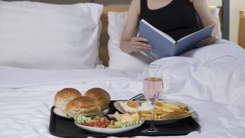 A bed with a tray of breakfast including eggs, bread, and a drink.