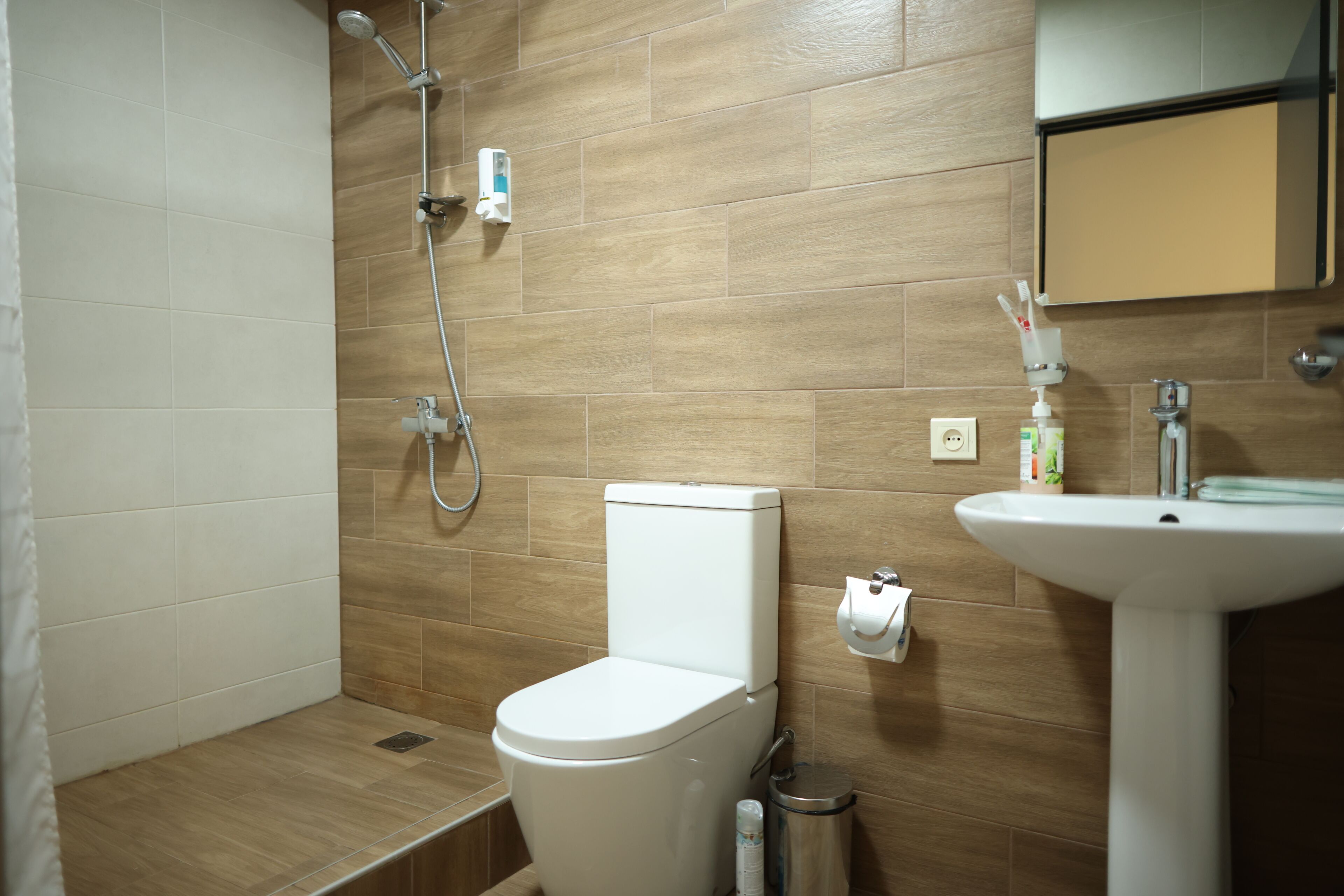 Une salle de bain équipée d’une douche, de toilettes, d’un lavabo et d’un miroir.