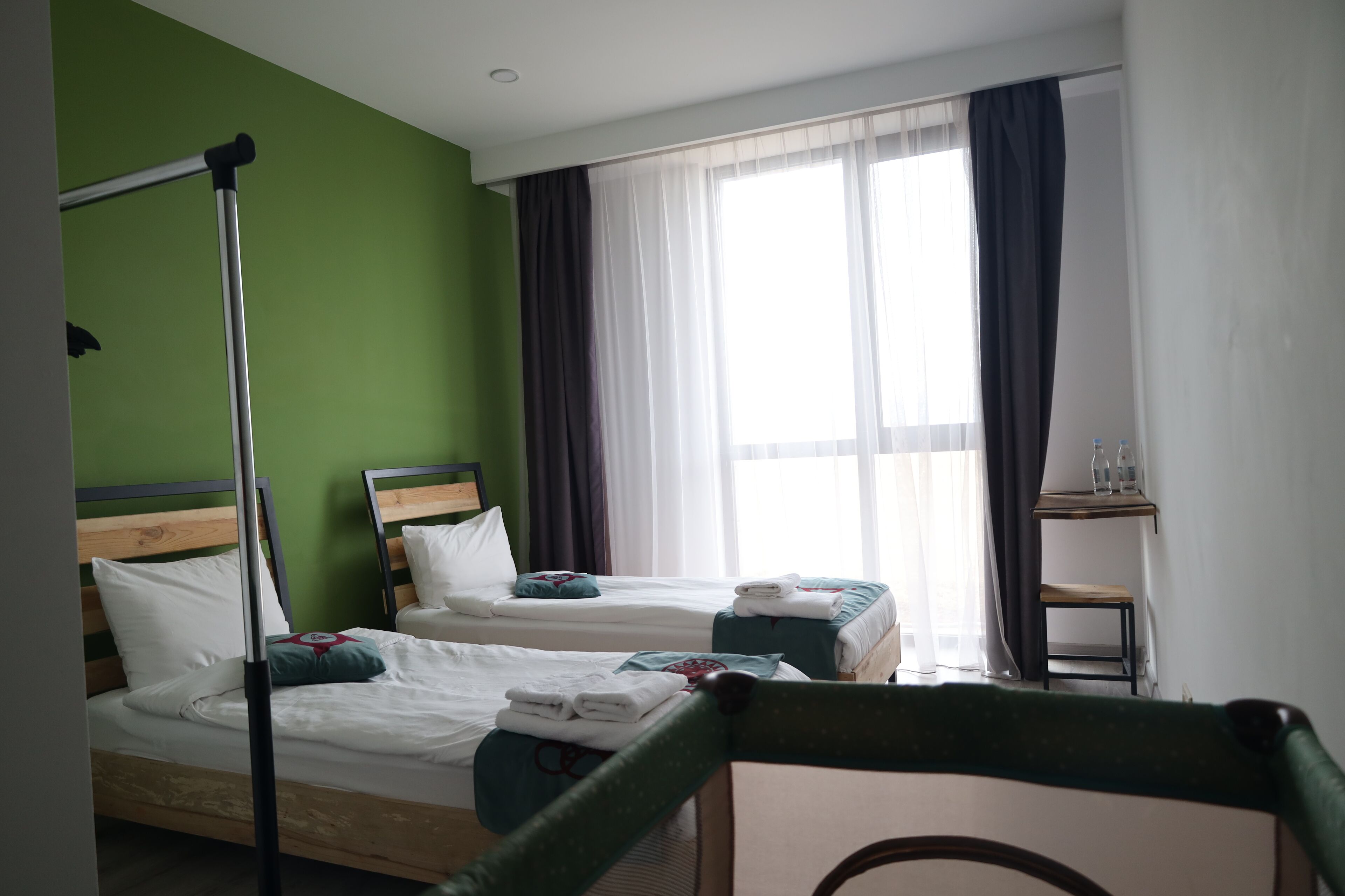 A hotel room with two single beds, a small table, and a chair.