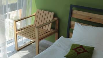 A room with a bed, a wooden chair, and a view through a window.