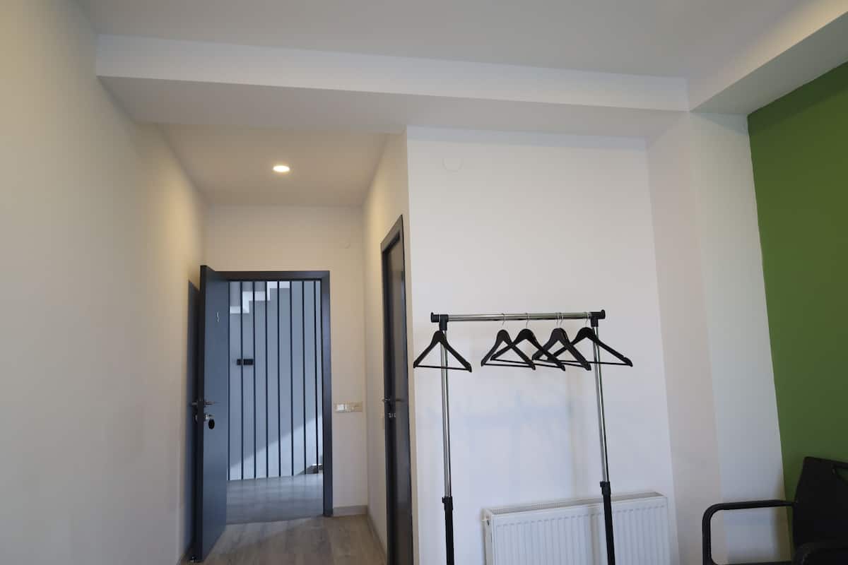 Un pasillo con un perchero, un radiador y una puerta que da a otra habitación.