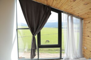 Una habitación con un ventanal grande, techo de madera y cortinas.