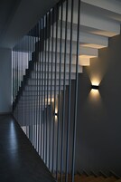 Una escalera moderna con barandilla de diseño minimalista e iluminación integrada en la pared.