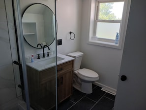 A bathroom with a toilet, sink, and mirror. - Salmon River Getaway - Firepit, BBQ & River Views (Richland)