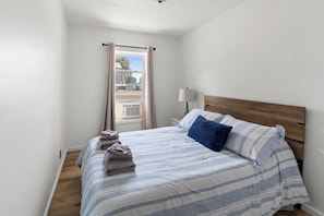A bedroom with a bed, pillows, a bedside lamp, and a window with curtains. - Salmon River Getaway - Firepit, BBQ & River Views (Richland)