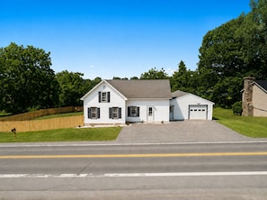 A two-story house with a garage, a driveway, and a wooden fence.