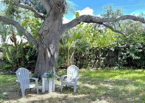 Sit and unwind in a serene garden setting with two comfortable chairs and a small table.