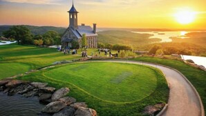 A historic building with a tower, surrounded by a well-maintained lawn and a curved pathway. - Cozy Condo - Table Rock Lake Community in Hollister, MO (Hollister)