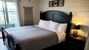 A neatly made bed with a dark headboard, white bedding, and a bedside lamp. - Cozy Condo - Table Rock Lake Community in Hollister, MO (Hollister)
