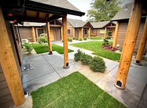 A courtyard with wooden pillars, a covered walkway, and a well-maintained lawn.