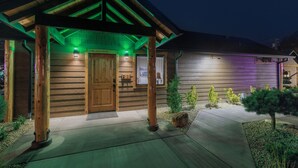 A wooden cabin with a covered porch, a wooden door, and a small garden with rocks and plants. - Bear Mountain -Suite 4 (Grants Pass)