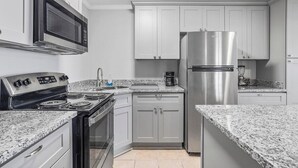 Une cuisine équipée d’une cuisinière, d’un four à micro-ondes, d’un réfrigérateur et de plans de travail en granit.