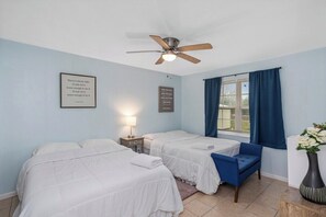 A hotel room with two beds, a ceiling fan, a window with curtains, a bedside lamp, and motivational quotes on the walls. - Rest Nest Lounge Cozy Spot for Fun and Calm - HAR3 (Iowa)