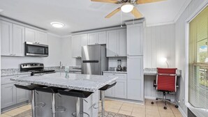 Une cuisine dotée d’un îlot central, d’appareils électroménagers en acier inoxydable et d’un ventilateur de plafond.