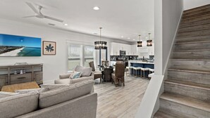 Una sala moderna con sofá, comedor, cocina y una escalera.
