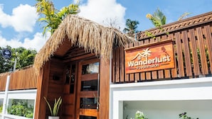 A wooden building with a thatched roof entrance and a sign reading "Wanderlust Fawahmulah".