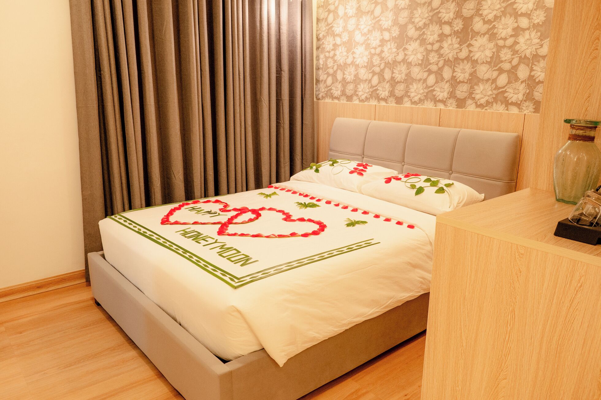 Una cama con colcha floral y una decoración en forma de corazón que dice "HONEYMOON".