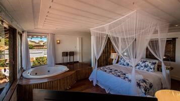 Un dormitorio con cama con dosel, una zona de estar con vistas y un jacuzzi.