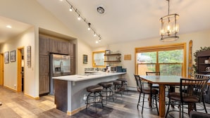 A spacious kitchen with a central island, bar stools, and a dining table. - Walk to the Lifts/Private Garage/Hot Tub Access/Custom Kitchen (Keystone)