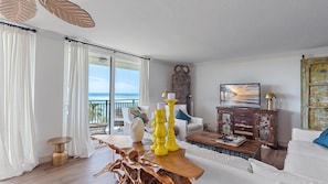 A living room with a wooden coffee table, white sofas, a TV, and a view of the ocean. - Luxury, Gulf Front Siesta Towers, Pool, Walk to Village (Siesta Key)