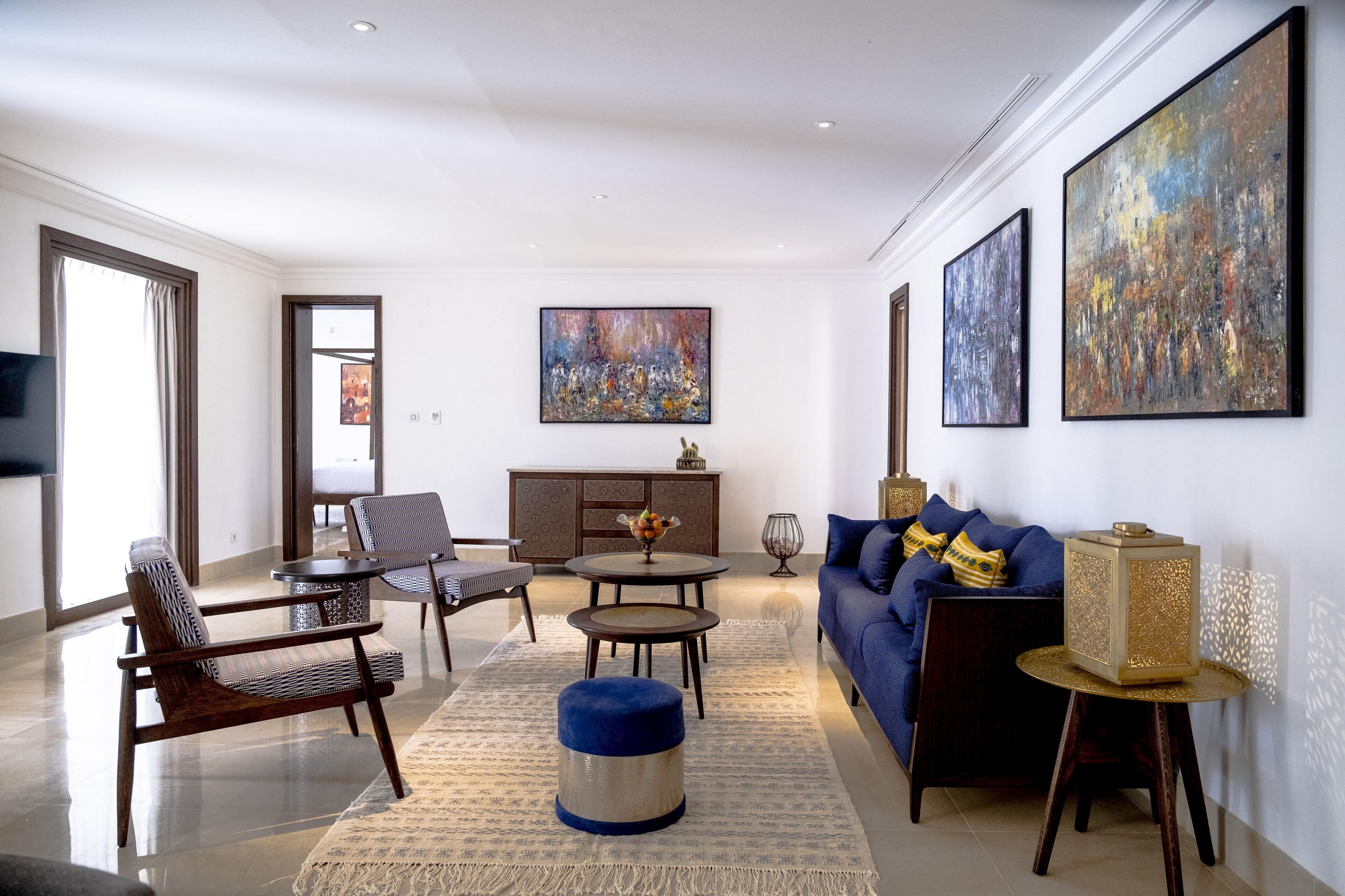 A modern living room with a sofa, chairs, a coffee table, and artwork on the walls.