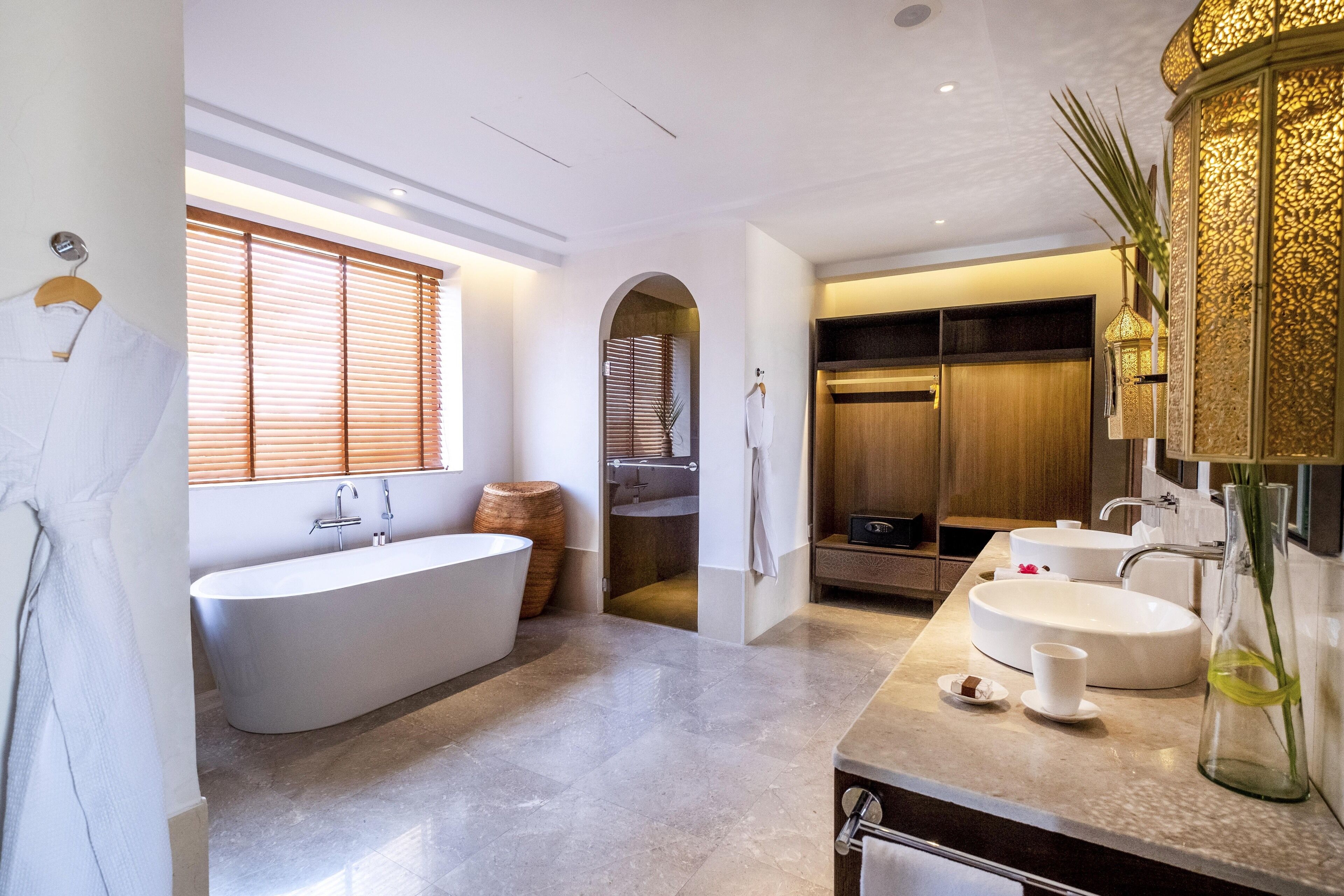 A modern bathroom with a freestanding bathtub, two sinks, and a vanity area.