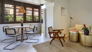 A modern living room with a dining area, large windows, and a view of buildings. - Canvas Apartments & Lofts Girona, Situados en el río Onyar (Girona)