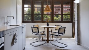 A modern kitchen with a dining area, large windows, and a hanging light fixture. - Canvas Apartments & Lofts Girona, Situados en el río Onyar (Girona)