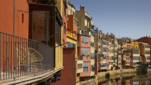 A row of colorful buildings with balconies and a canal in the foreground. - Canvas Apartments & Lofts Girona, Situados en el río Onyar (Girona)