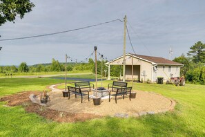 A covered outdoor seating area with a fire pit, surrounded by a grassy field and a house in the background. - Relax Fireside! Home < 1 Mi to Tryon International (Mill Spring)