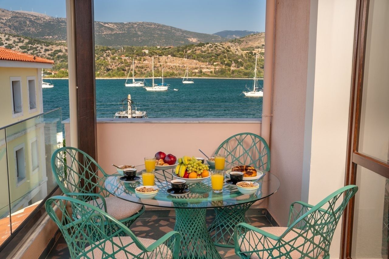 A balcony with a table set for breakfast, overlooking a marina with boats.
