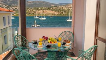 A balcony with a table set for breakfast, overlooking a marina with boats.