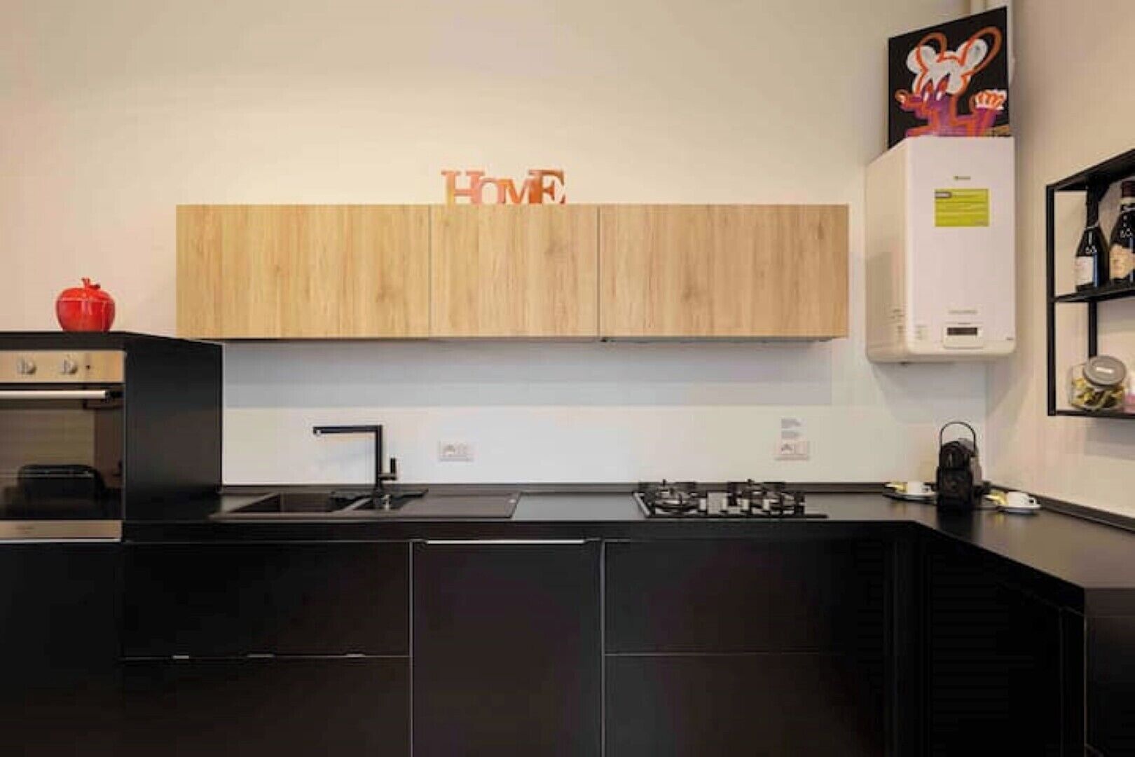 Una cocina moderna con armarios de madera, encimera negra y campana extractora de acero inoxidable.