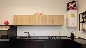 Eine moderne Küche mit Holzausstattung, einer schwarzen Arbeitsplatte und einer Edelstahl-Dunstabzugshaube.