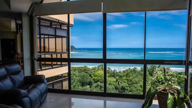 Una sala de estar moderna con un ventanal que ofrece vistas a la costa.