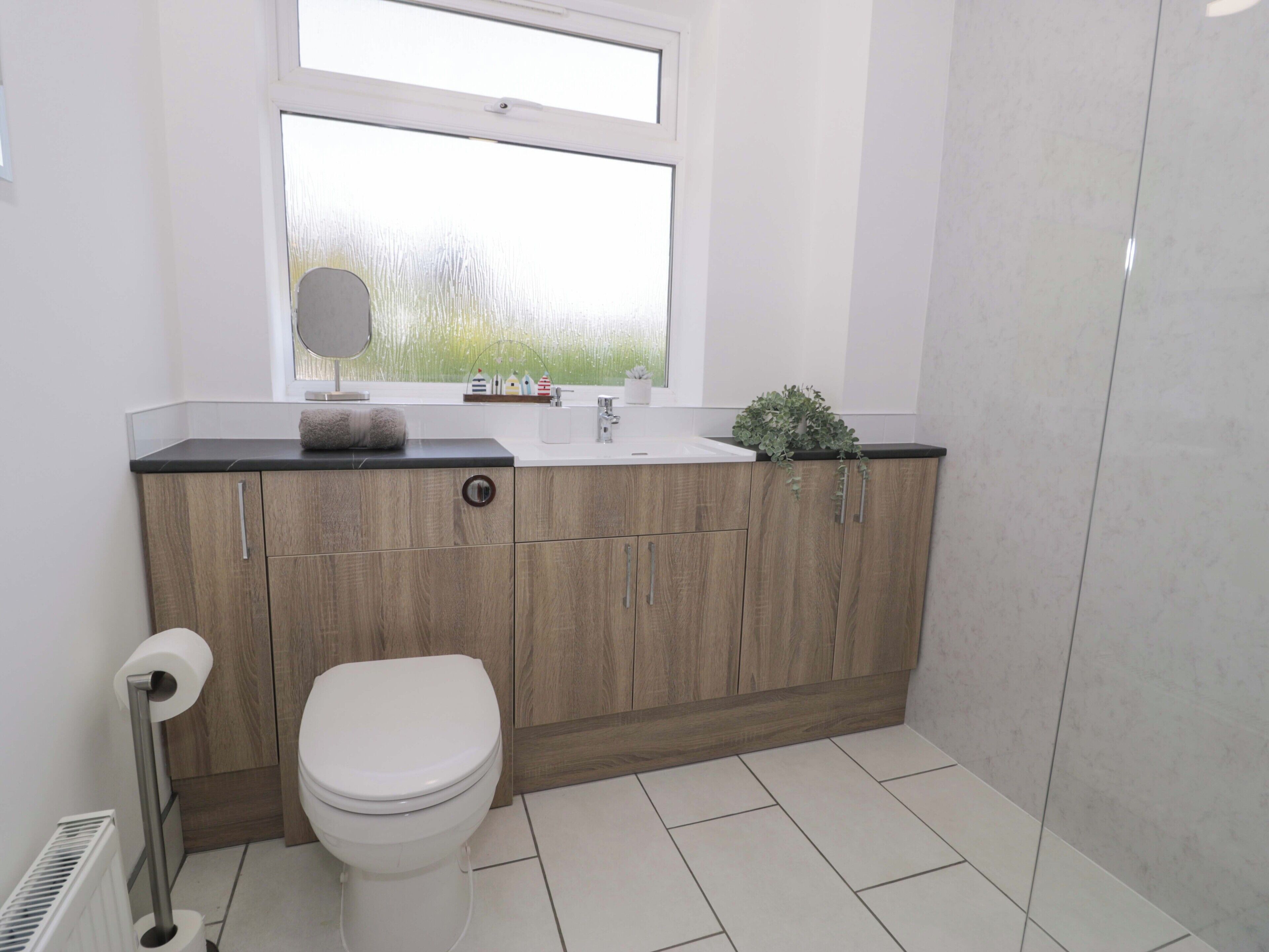 A modern bathroom with a toilet, sink, and window.