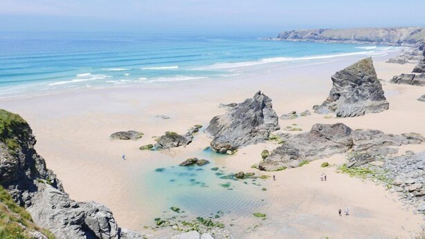 Una playa costera con afloramientos rocosos y agua cristalina.
