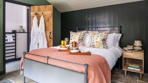 Un dormitorio ordenado con cama, mesita de noche y un perchero en la pared.