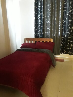 Cozy retreat with a comfortable bed, geometric-patterned curtains, and a warm atmosphere.