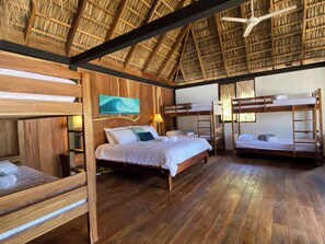 Une pièce avec un plafond en bois, des lits superposés, un lit avec une tête de lit en bois et un tableau accroché au mur.