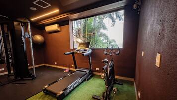 A gym with a treadmill, stationary bike, and weight equipment.