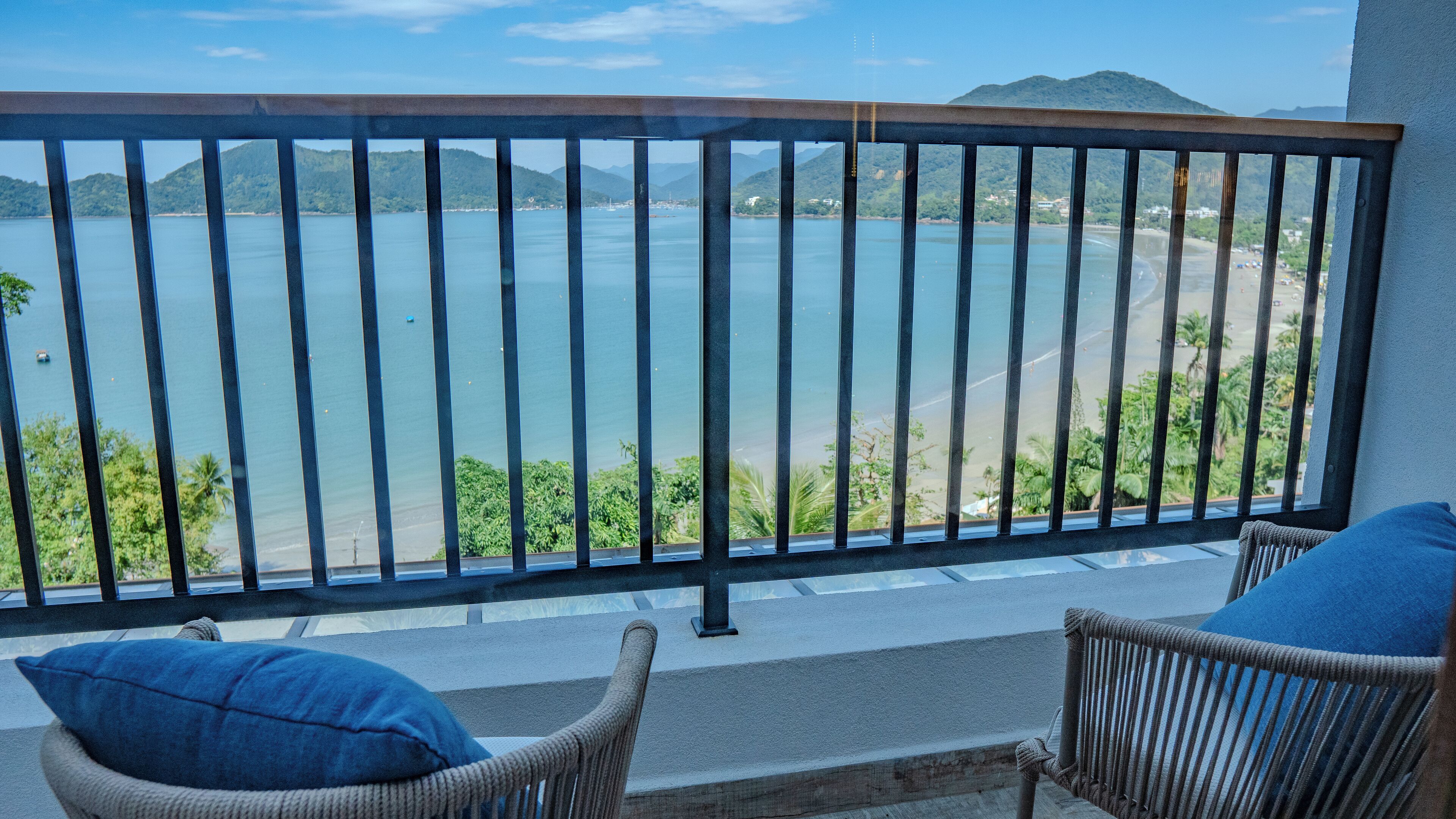 Uma varanda com vista para um mar tranquilo e montanhas ao longe.