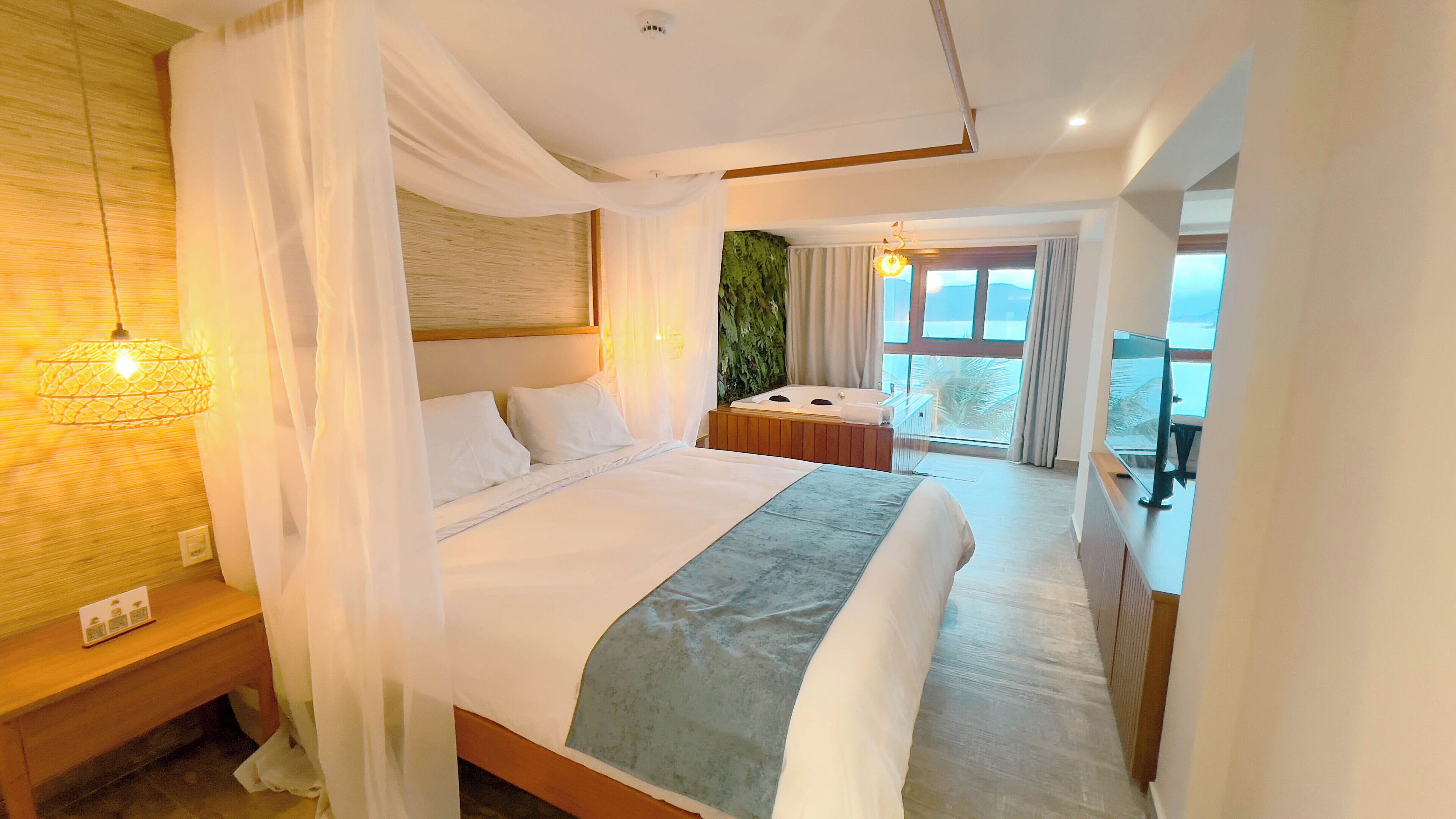 A spacious bedroom with a large bed, a sitting area with a view, and a balcony.