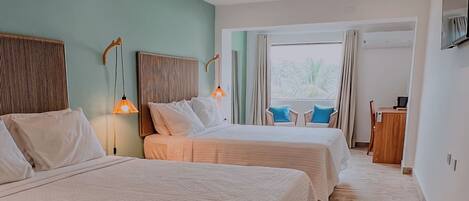 A hotel room with two beds, a desk, a chair, and a window with curtains.