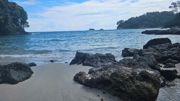 A beach with large rocks in the foreground and a clear view of the ocean. - Beautiful 2bd 2 ba villa w/lush yard, gated community 15 min from Manuel Antonio (Quepos)